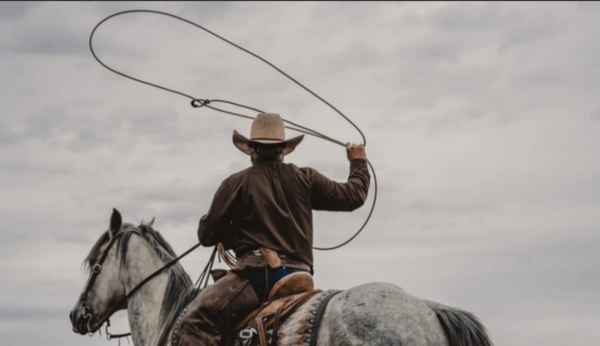 man on horse swings lasso above his head